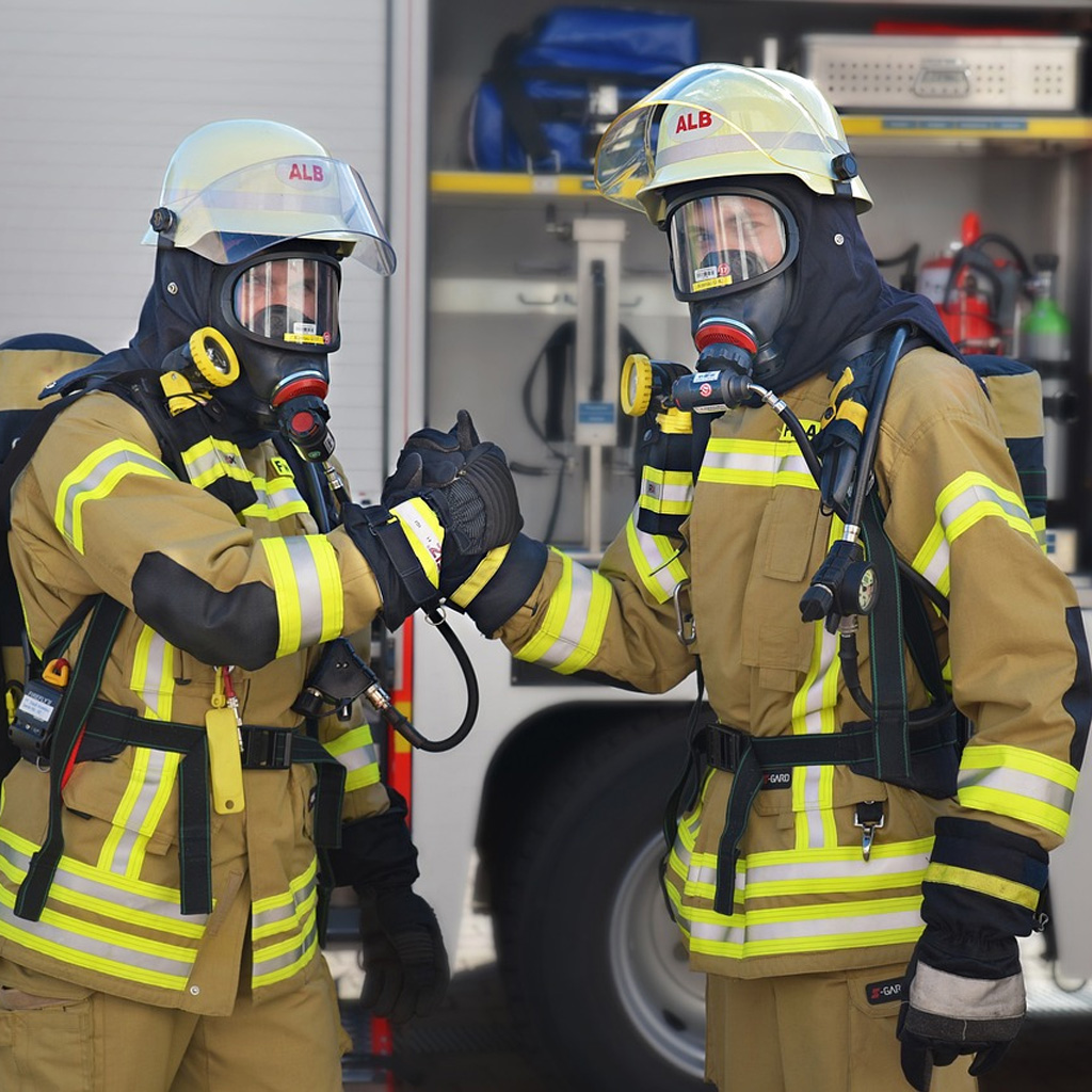 Bombeiro utilizando roupa de aproximação completa com capacete, luvas e máscara em operação.