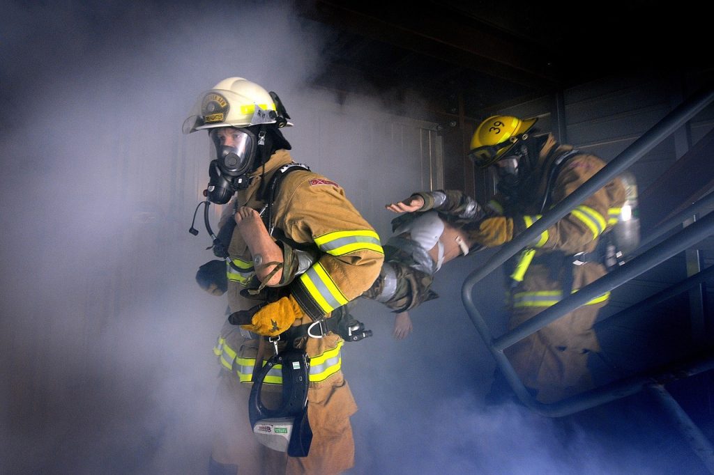 Bombeiro utilizando roupa de aproximação completa com capacete, luvas e máscara em operação.